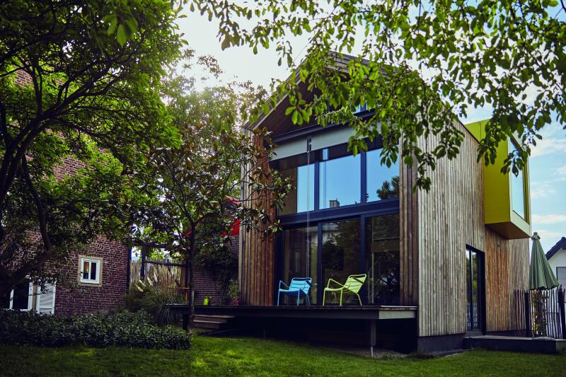 Mit Holz verkleidetes Tiny House mit Balkon und Garten